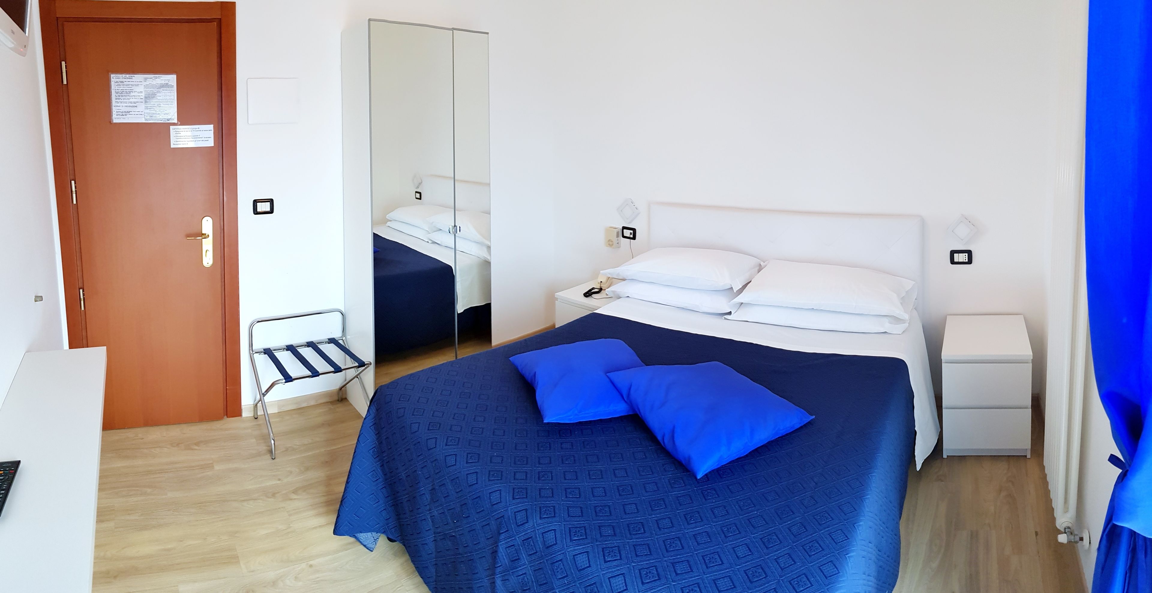 Une chambre à coucher comprenant un lit, des tables de chevet, une chaise, une armoire et une porte.