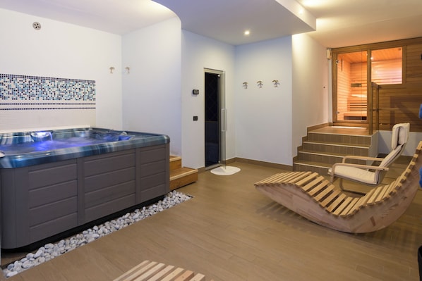 Un moderno spa con jacuzzi, asientos de madera y una escalera que lleva a una zona de sauna.