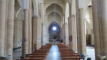 Interior de iglesia con hileras de bancas de madera y columnas de piedra.