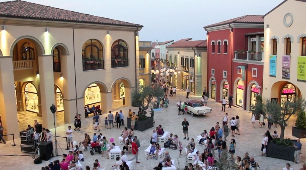 A bustling pedestrian street lined with historic buildings, featuring shops and cafes.