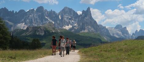 A group of hikers on a gravel path with a mountainous landscape in the background.