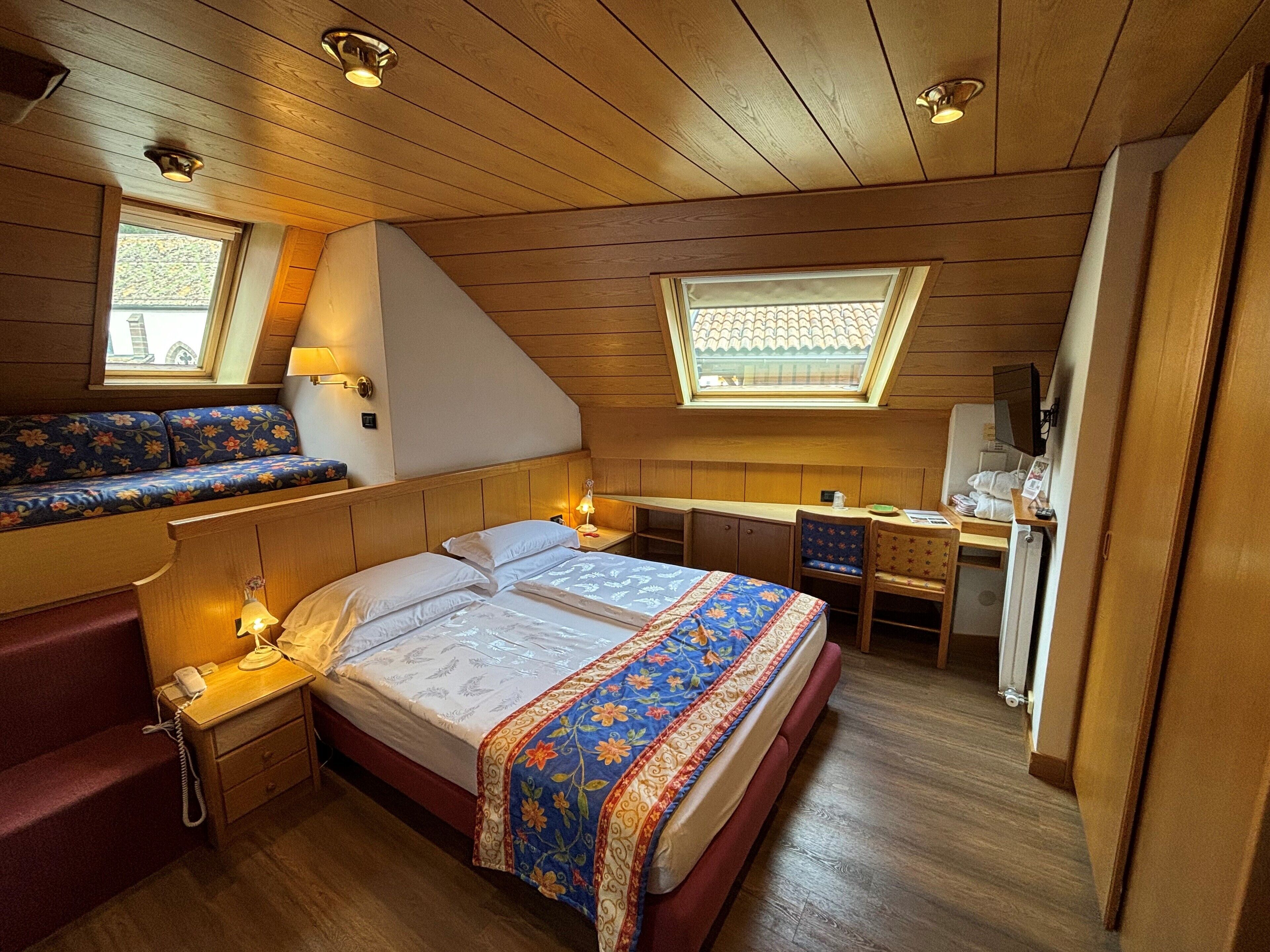 Une chambre confortable avec un lit, des tables de chevet, un bureau et un banc.