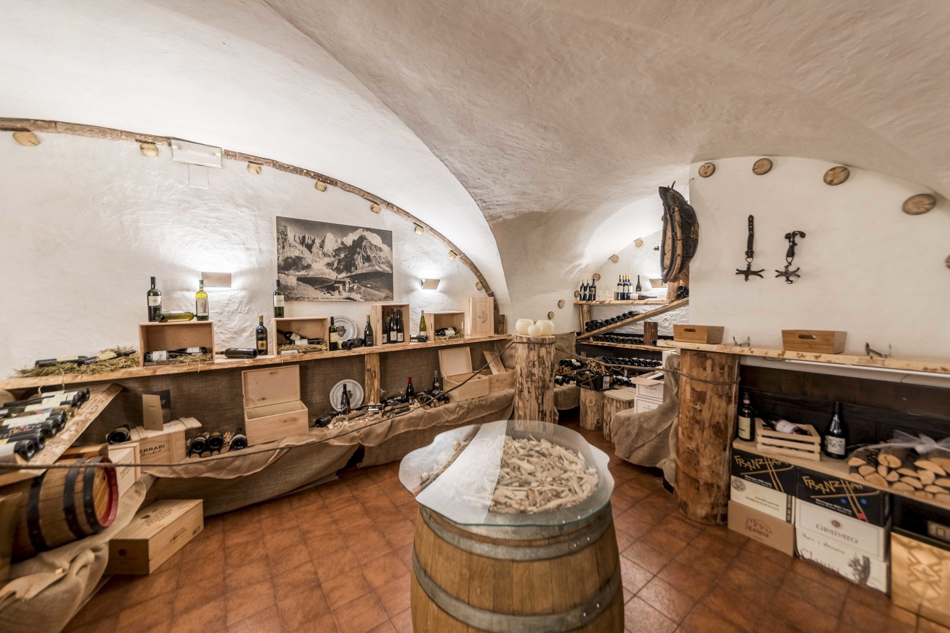 Un interior con estantes de madera, botellas de vino y barriles.
