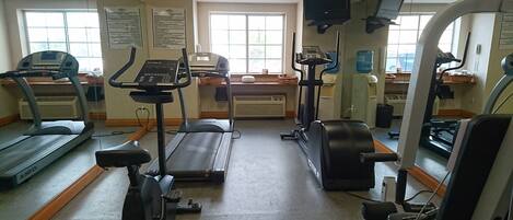 Un gimnasio con cintas de correr, elípticas y equipo de pesas.
