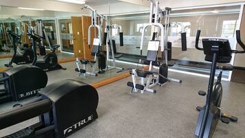 Un gimnasio con diversos equipos de ejercicio, como cintas de correr, máquinas de pesas y una máquina de remo.