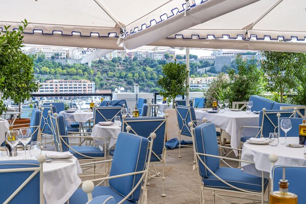 Enjoy meals in a serene outdoor setting with a scenic hillside view.