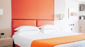 A hotel room with a bed, a nightstand, a red headboard, a white wall, a framed picture, and a lamp.