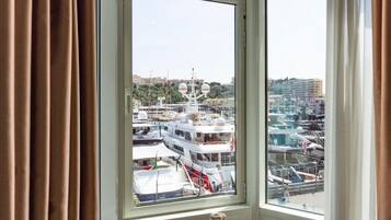 Een kamer met een groot raam met uitzicht op een jachthaven met verschillende liggende boten.