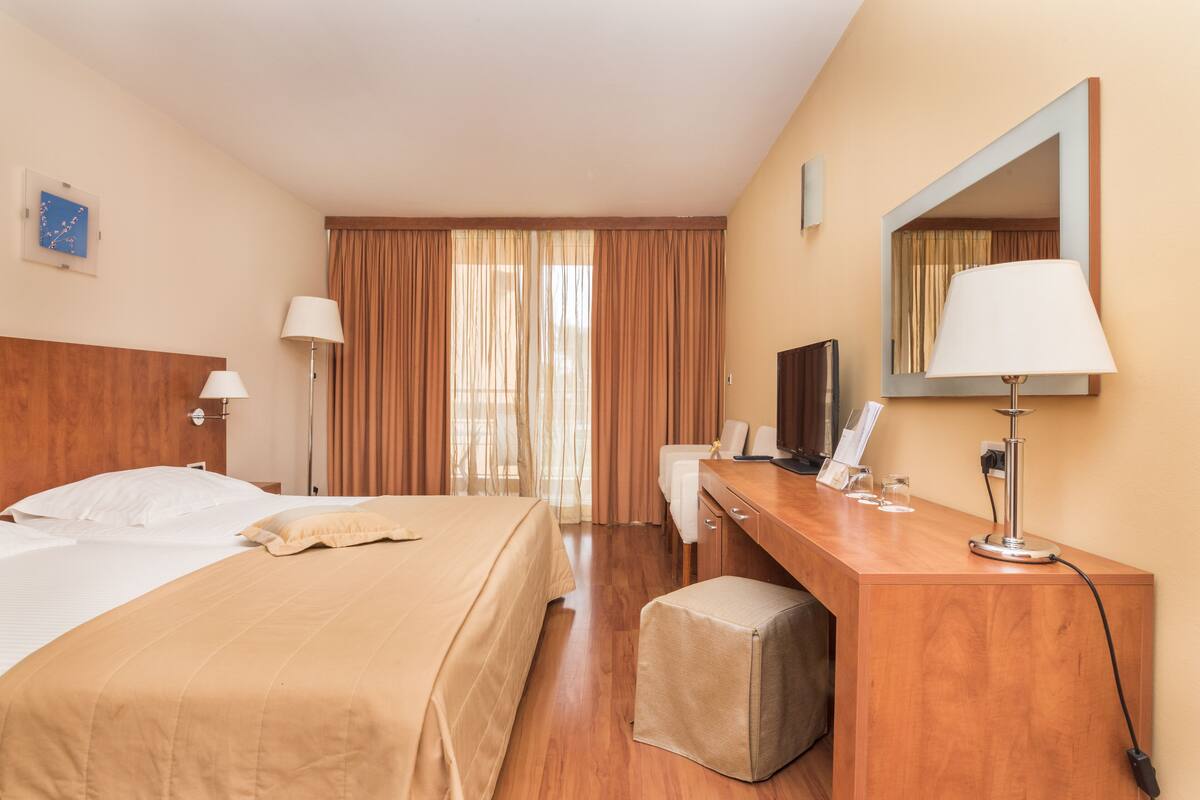 Une chambre d’hôtel équipée d’un lit, d’un bureau, d’une chaise et d’un téléviseur.