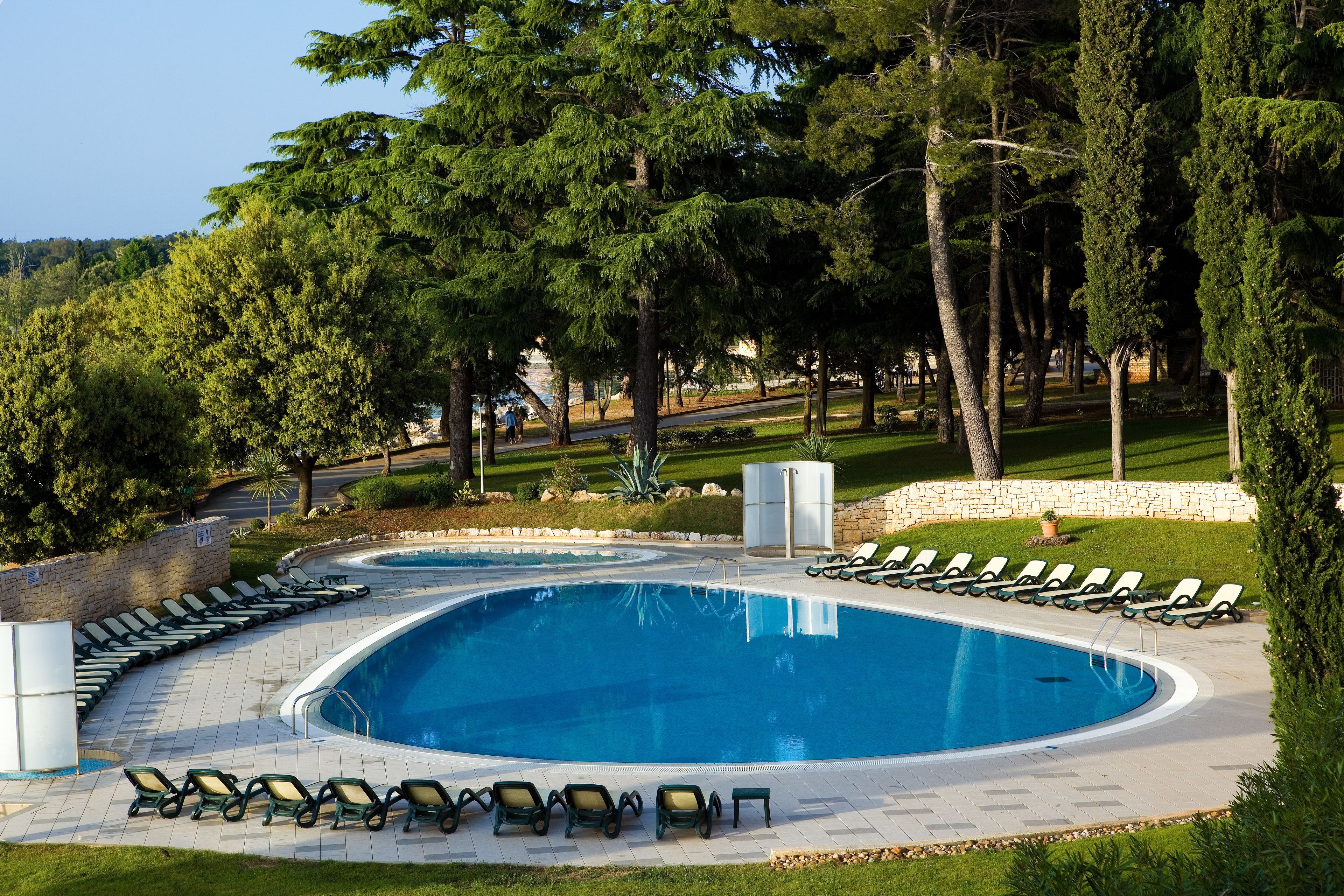 A swimming pool with lounge chairs and a stone wall.