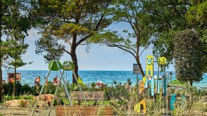 A playground with swings and climbing structures near a body of water. - Hotel Umag Plava Laguna (Umag)