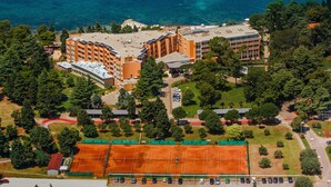 An aerial view of a hotel with multiple buildings, a tennis court, and a parking lot. - Hotel Umag Plava Laguna (Umag)