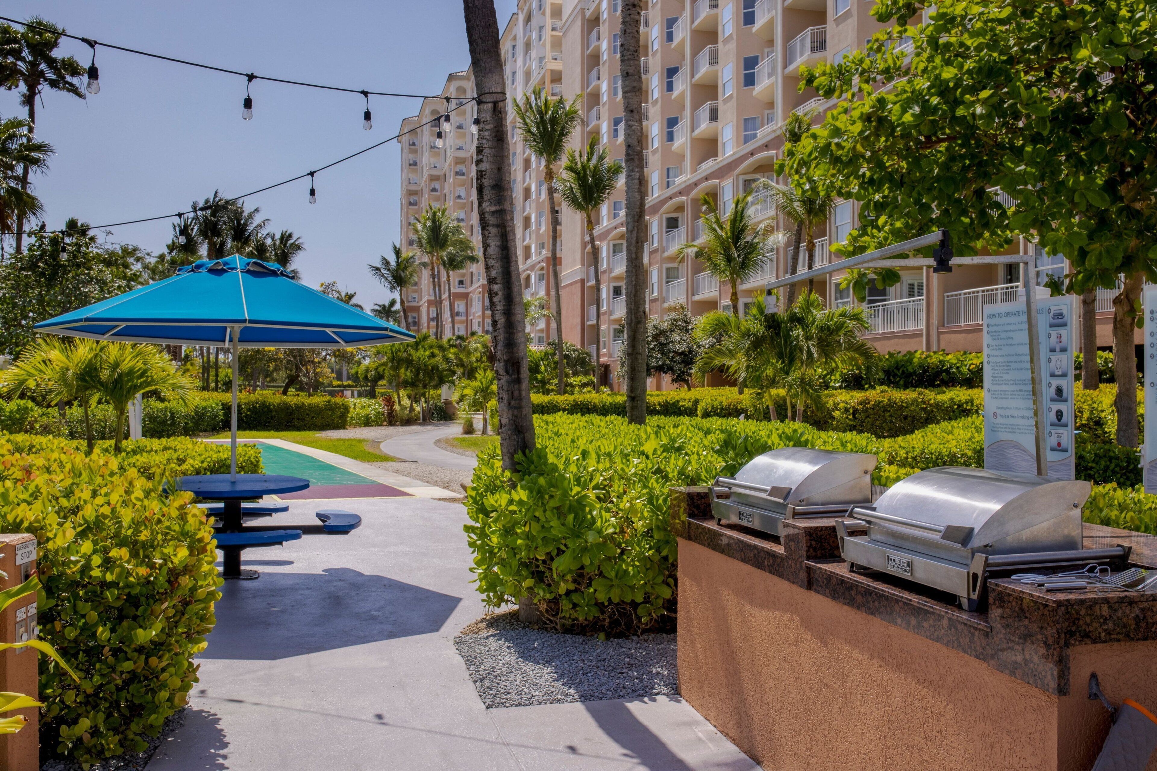 A resort courtyard with outdoor seating, a barbecue grill, and a swimming pool.