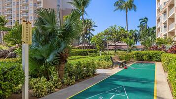 Un patio con una cancha de juego de hojalata, palmeras y un cartel que indica una distancia de 70 metros.