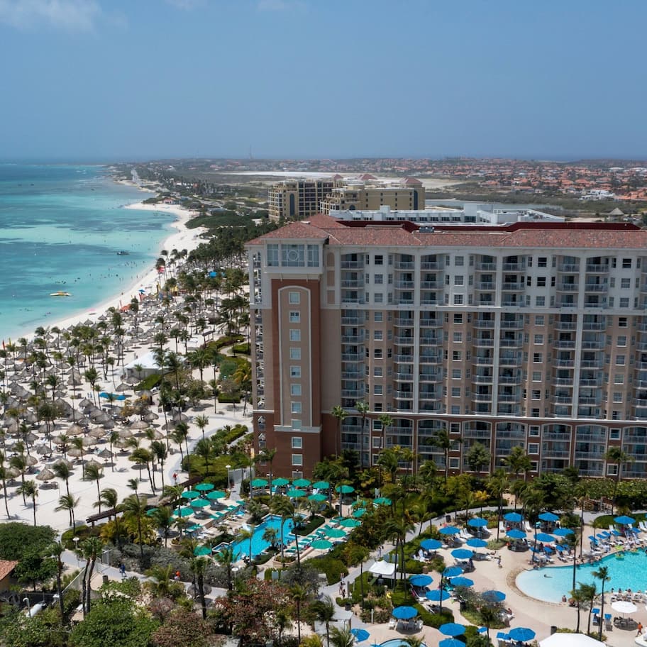 A resort with a large pool area, beach access, and a view of the ocean.