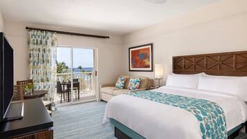 A hotel room with a bed, a desk, a chair, a TV, and a balcony with a view.