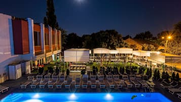 Una piscina techada, una piscina al aire libre de temporada, sombrillas