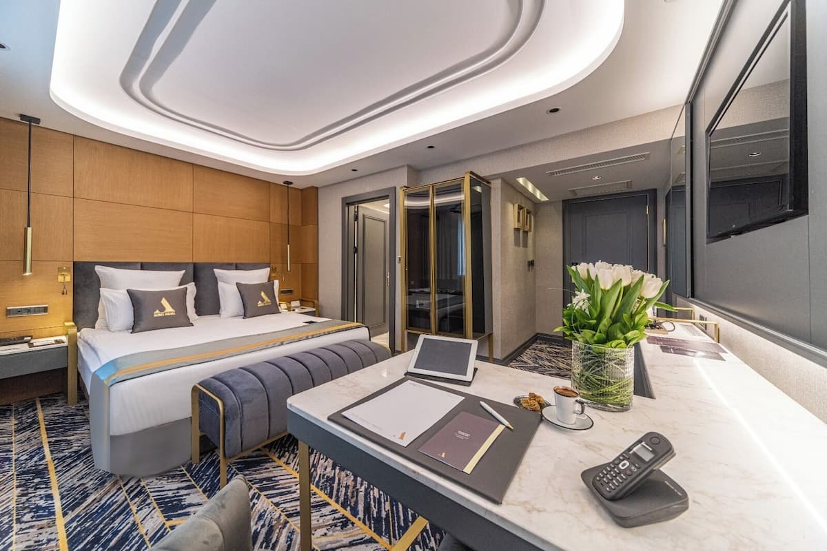 A modern hotel room with a bed, desk, and a large mirror.