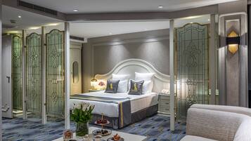 Una habitación de hotel moderna con una cama grande, una mesita de noche con una bandeja de aperitivos y un espejo decorativo.
