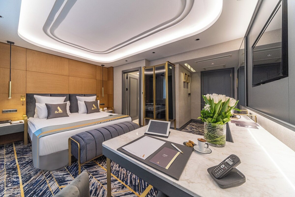 Ein modernes Hotelzimmer mit Bett, Schreibtisch und einem großen Spiegel.