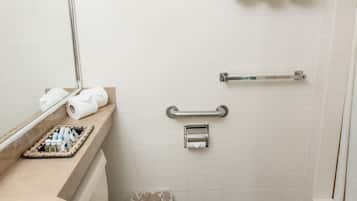 A bathroom with a toilet, sink, mirror, towel rack, and shower area.
