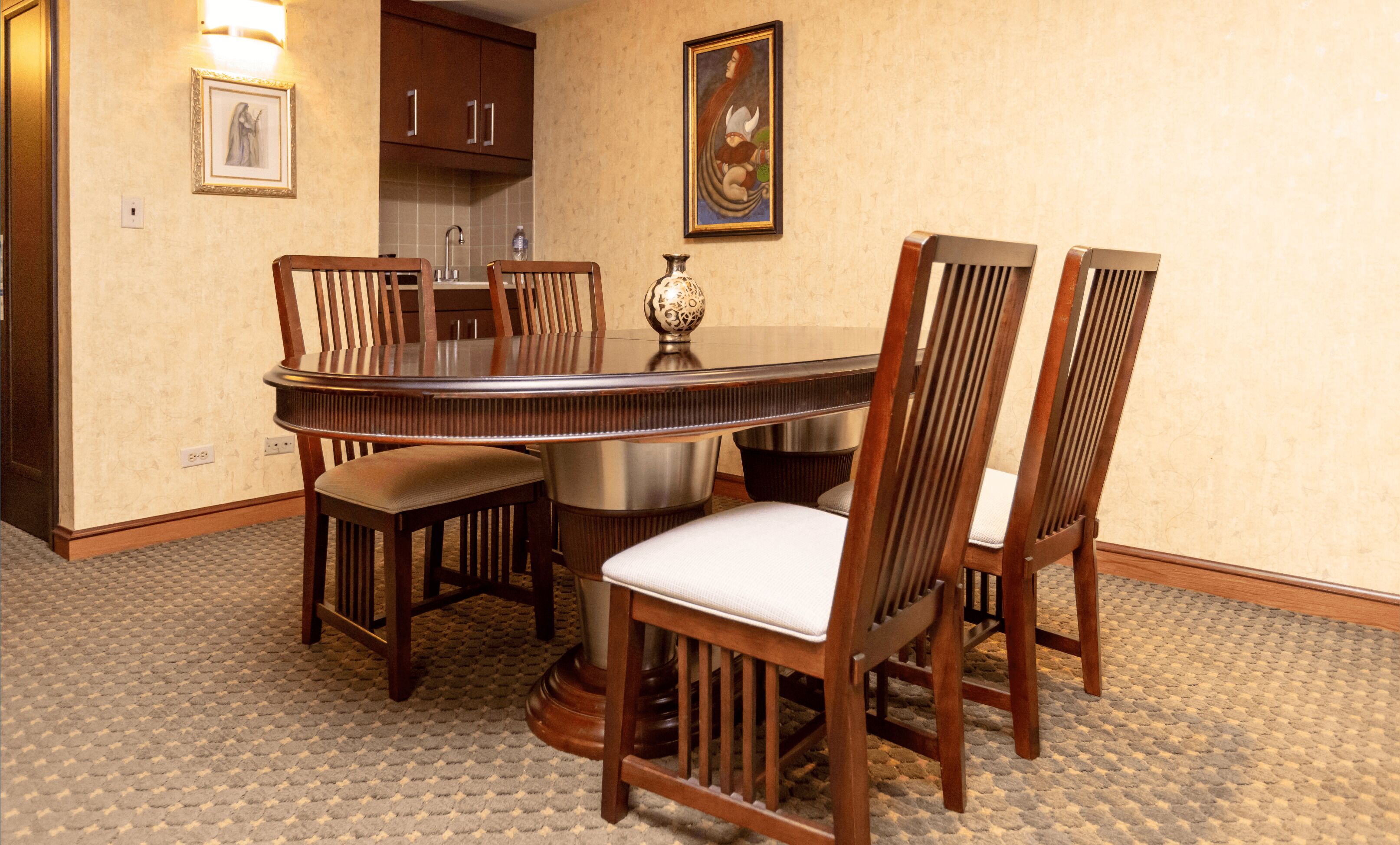 Comedor con mesa redonda rodeada de sillas de madera con asientos acolchados.
