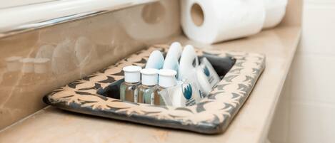 Uma toucador de banheiro com uma bandeja estampada contendo artigos de higiene pessoal e um rolo de papel higiênico.