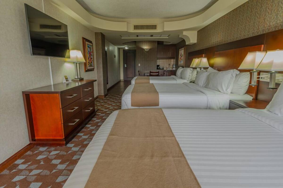 Une chambre d’hôtel avec deux lits, une télévision, un bureau et une kitchenette.