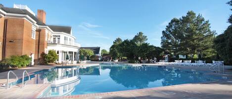 A swimming pool with a clear blue water surface, surrounded by a paved deck.