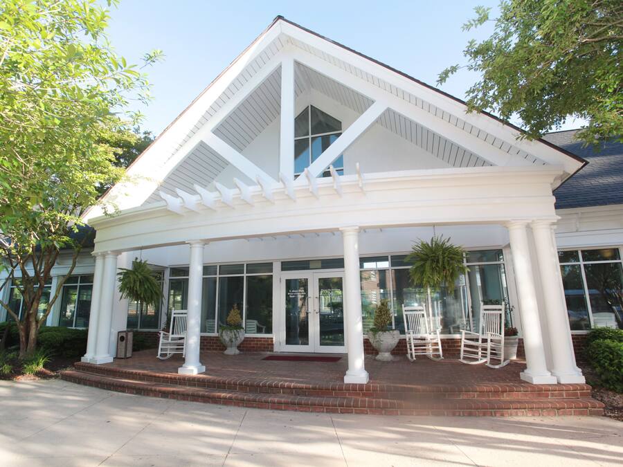 A covered outdoor area with white columns, a brick entrance, and potted plants.