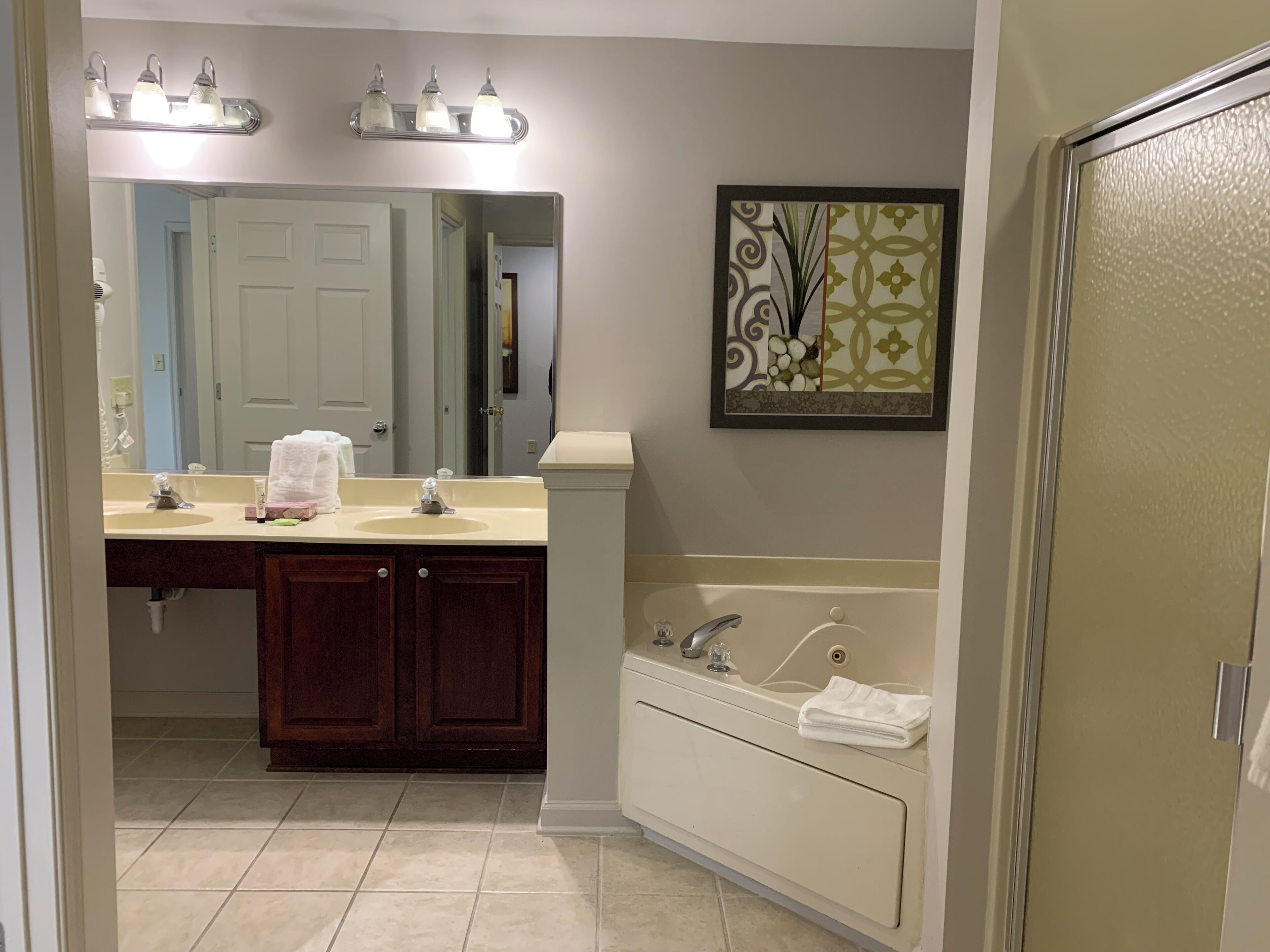 A bathroom with a vanity, sink, mirror, and bathtub.