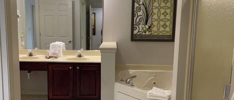 A bathroom with a vanity, sink, mirror, and bathtub.