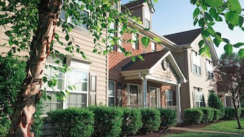 A two-story house with a front porch, brick facade, and a well-maintained lawn.