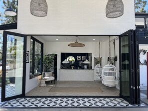A modern entrance with glass doors, a herringbone floor pattern, and a central seating area with a bench and potted plant. - Anaheim Maingate Inn (Anaheim)