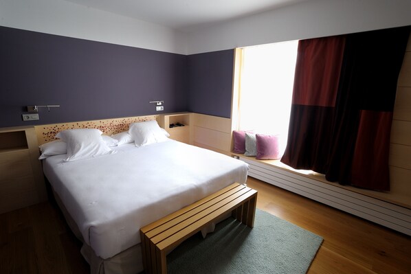 A neatly arranged bedroom with a bed, bedside tables, a bench, and a window with curtains. - Hotel Continental Balneario de Panticosa (Panticosa)