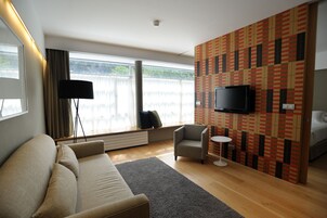 Una sala moderna con un sofá, un sillón y una pequeña mesa redonda.