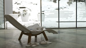 Een moderne kamer met een groot raam, een witte stoel en een paar slippers op de vloer.