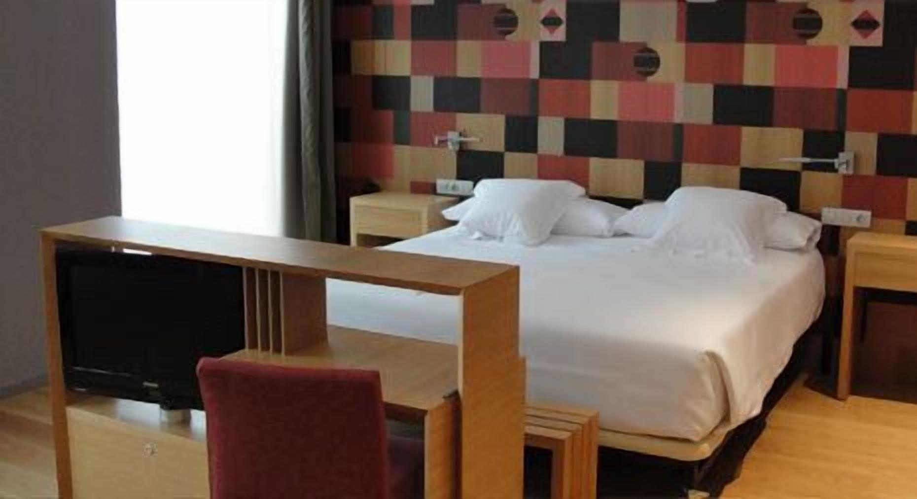 Una habitación de hotel con cama, televisión y escritorio.
