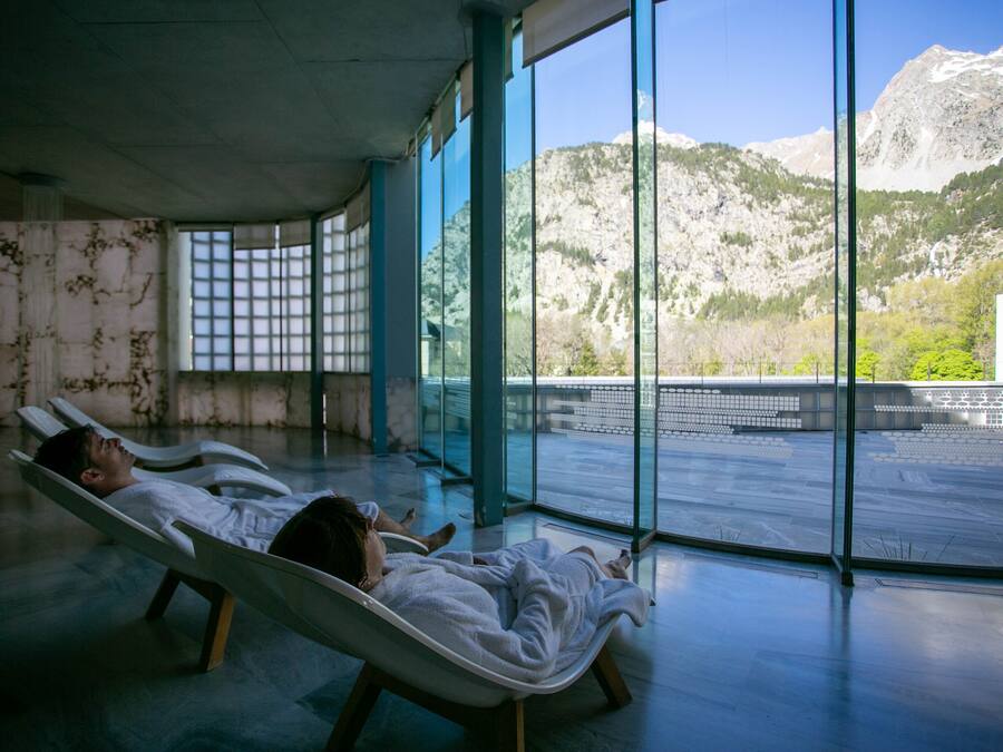 Two reclining chairs in a room with large windows overlooking a mountainous landscape.