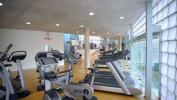 Un gimnasio con cintas de correr, elípticas y bicicletas estáticas.