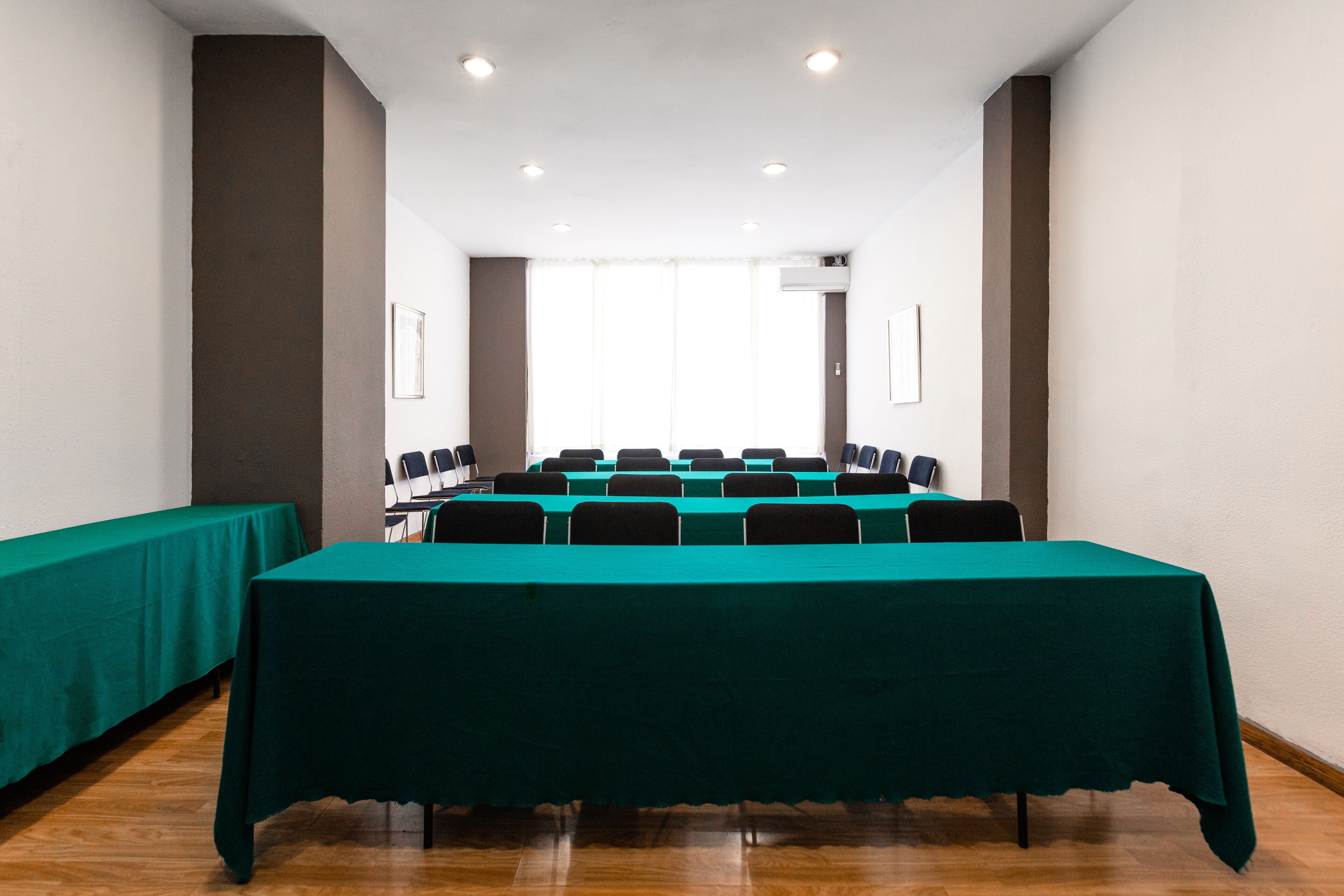 A conference room with a long table, chairs, and a green tablecloth.