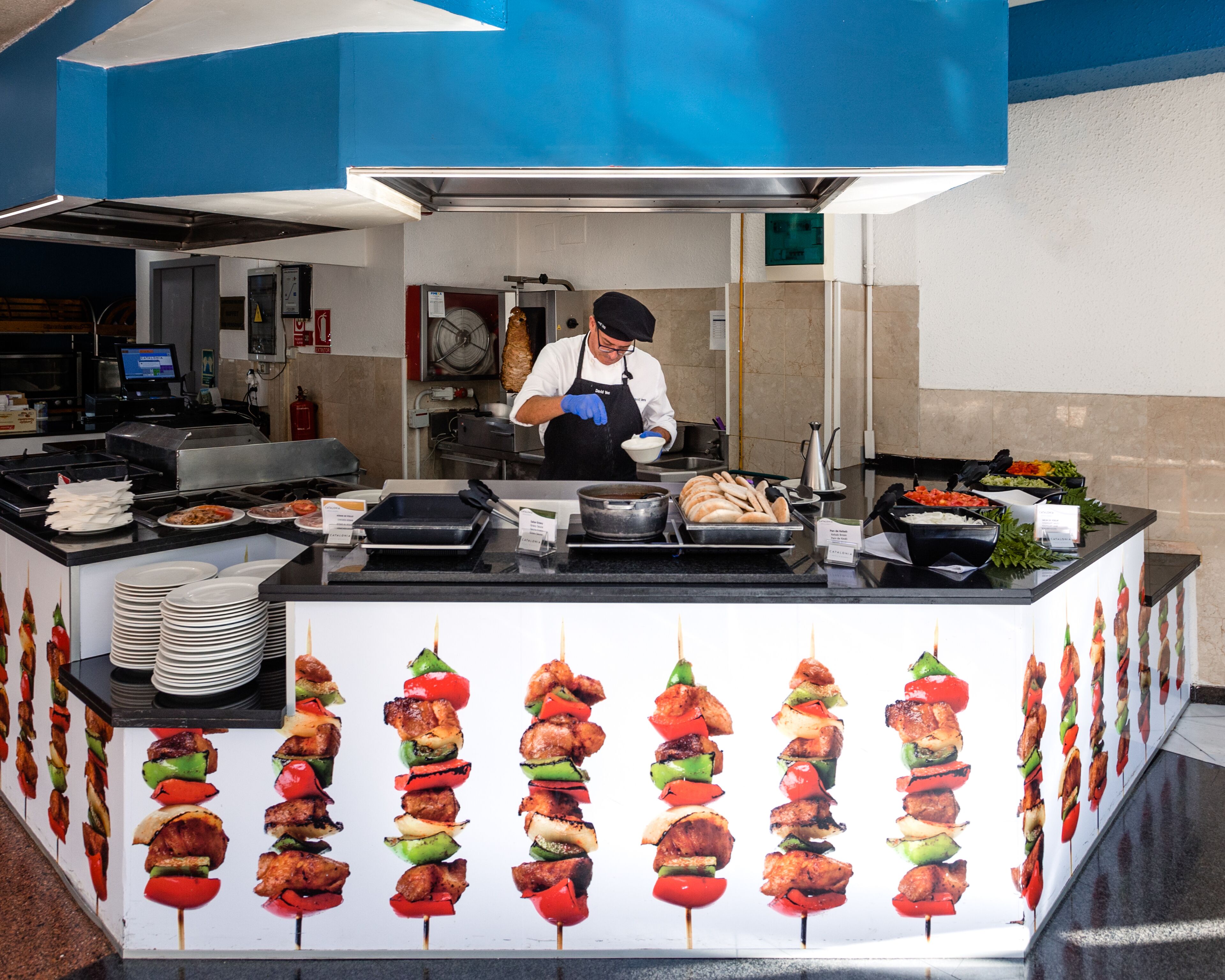 A buffet setup with various food items and a chef preparing food.