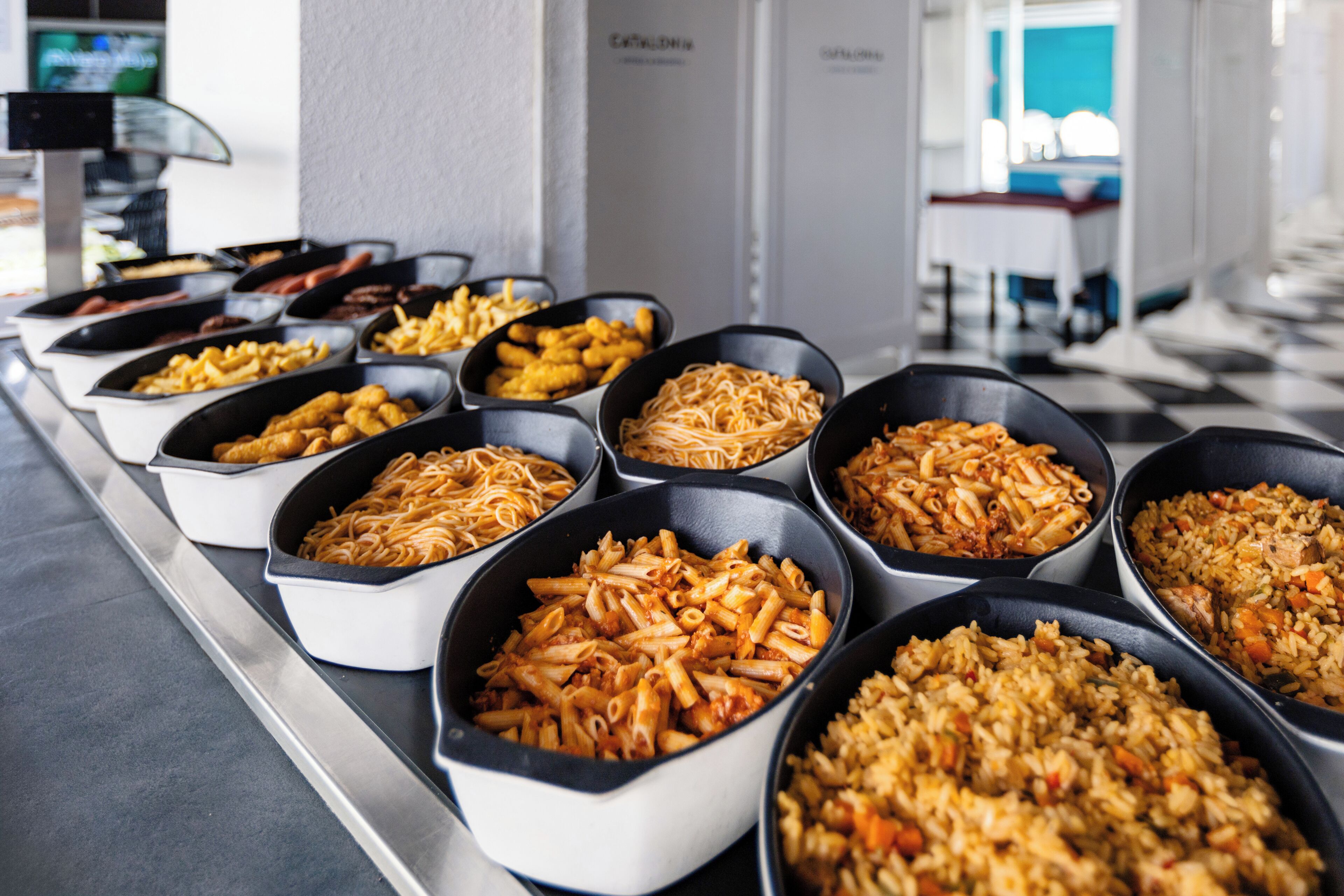 A buffet with various pasta dishes and a checkered floor.