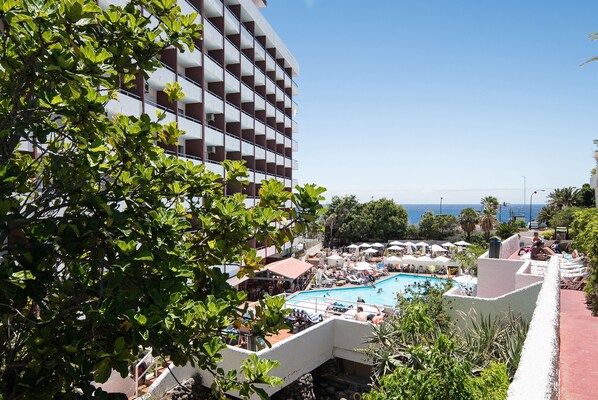 Un hotel con piscina, zona de estar al aire libre y vista al mar.