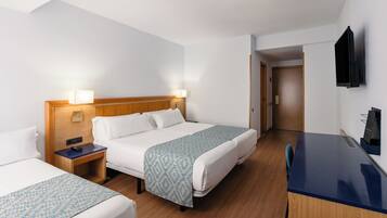 A hotel room with two beds, a desk, and a TV.