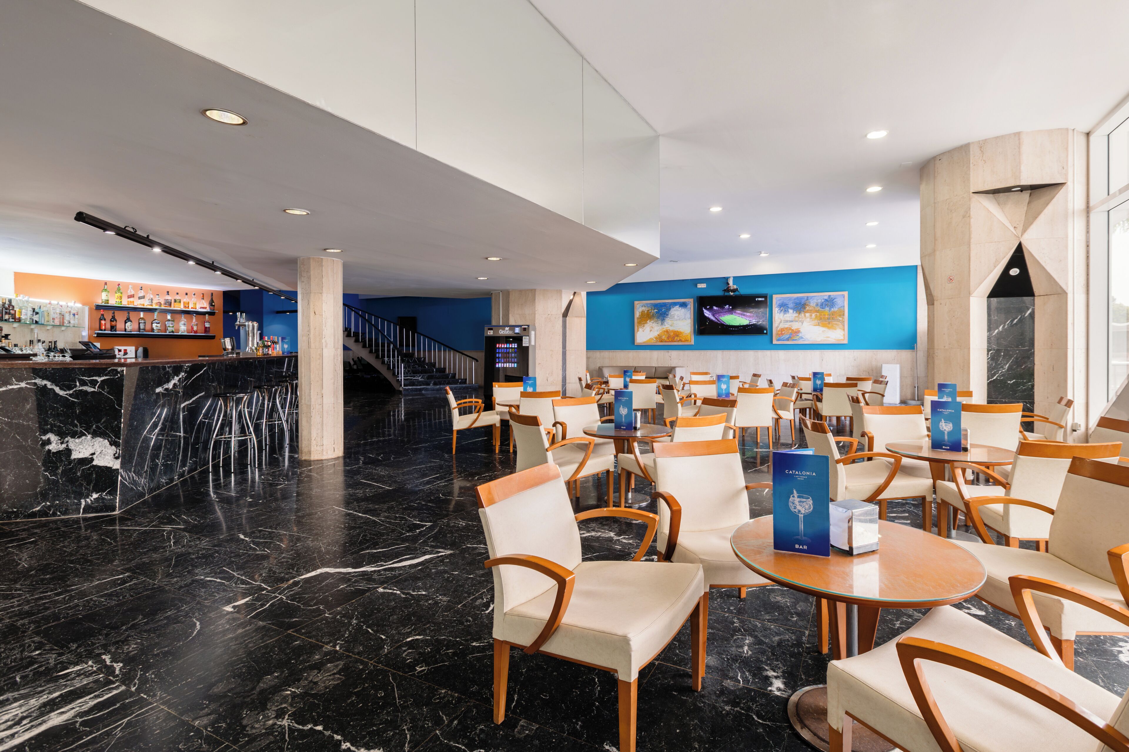 Un moderno vestíbulo de hotel con pisos de mármol, una zona de bar y diferentes disposiciones de asientos.