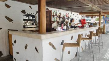 A bar area with a counter, stools, and a coffee machine.