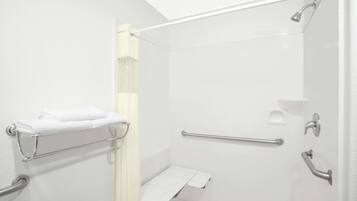 A modern bathroom with a walk-in shower, grab bars, a towel rack, and a toilet with a safety bar.