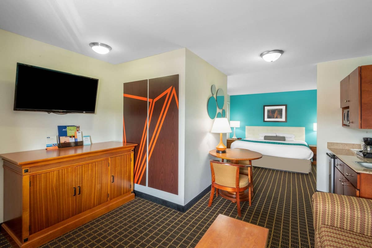 Ein Hotelzimmer mit Bett, Schreibtisch, Stuhl, Fernseher, Kleiderschrank und Bad.