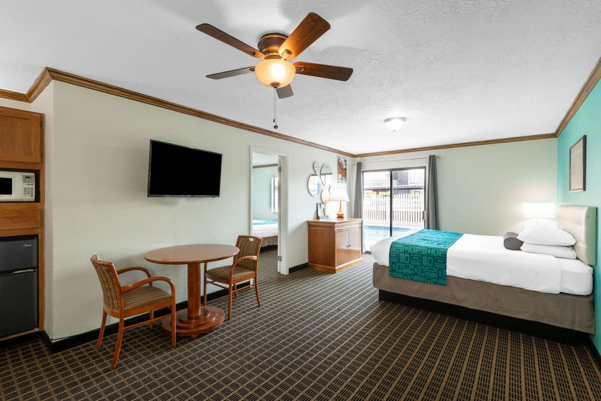Ein Hotelzimmer mit Bett, Schreibtisch mit Stuhl, Deckenventilator, Fernseher und Mikrowelle.